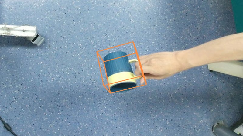 A mug held in a hand with its ground-truth 3D box